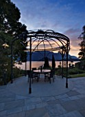 VILLA GIUSEPPINA  LAKE COMO  ITALY  - EVENING VIEW OF LAKE FROM THE TERRACE WITH METAL PERGOLA  TABLE AND CHAIRS: A PLACE TO SIT