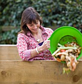 DESIGNER: CLARE MATTHEWS: FRUIT GARDEN PROJECT - CLARE COMPOSTING WITH A GREEN BUCKET FULL OF VEGETABLE PEELINGS