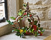 DESIGNER - JACKY HOBBS : CHRISTMAS DECORATION - RUSTY METAL CROWN IN WINDOWSILL WITH HOLLY LEAVES AND BERRIES