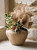 DESIGNER - JACKY HOBBS : CHRISTMAS DECORATION - CHRISTMAS PUDDING WRAPPED IN HESIAN  HOLLY BERRIES AND LEAVES  IN WINDOWSILL