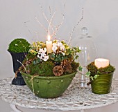 DESIGNER: JACKY HOBBS  LONDON: LIVING ROOM AT CHRISTMAS - GREEN GLAZED CONTAINERS WITH CANDLES AND CHRISTMAS DECORATIONS ON WHITE METAL TABLE