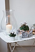 DESIGNER: JACKY HOBBS  LONDON - CHRISTMAS - DINING ROOM - WHITE METAL TABLE WITH GLASS CANDLE HOLDER AND WHITE CYCLAMEN IN CONTAINERS