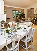 DESIGNER: JACKY HOBBS  LONDON - CHRISTMAS - DINING ROOM/ LIVING ROOM - DINING TABLE LAID FOR CHRISTMAS  SOFAS AND CHRISTMAS TREE