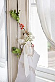 DESIGNER: JACKY HOBBS  LONDON: BEDROOM AT CHRISTMAS WITH HOLLY DECORATION TIED TO MIRROR FRONTED WARDROBE