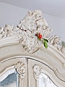 DESIGNER: JACKY HOBBS  LONDON: BEDROOM AT CHRISTMAS WITH HOLLY DECORATION TIED TO MIRROR FRONTED WARDROBE