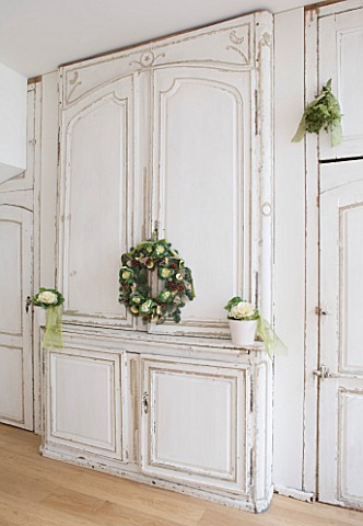 DESIGNER_JACKY_HOBBS__LONDON_CHRISTMAS_WREATH_ON_KITCHEN_DOORS_AND_WHITE_CONTAINERS_WITH_CABBAGES