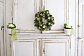 DESIGNER: JACKY HOBBS  LONDON: CHRISTMAS WREATH ON KITCHEN DOORS AND WHITE CONTAINERS WITH CABBAGES
