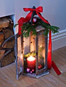 DESIGNER: JACKY HOBBS  LONDON: LIVING ROOM AT CHRISTMAS WITH WOODEN CANDLE HOLDER DECORATED WITH RIBBON AND FIR BRANCH
