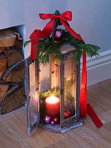 DESIGNER_JACKY_HOBBS__LONDON_LIVING_ROOM_AT_CHRISTMAS_WITH_WOODEN_CANDLE_HOLDER_DECORATED_WITH_RIBBO