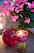DESIGNER: JACKY HOBBS  LONDON: THE LIVING ROOM AT CHRISTMAS WITH DINING TABLE SET WITH GLASS BALL  CANDLES AND PINK CYCLAMEN IN A CONTAINER