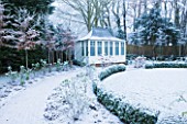 FORMAL TOWN GARDEN IN SNOW  OXFORD  WINTER: DESIGN BY LIZ NICHOLSON - LEAD ROOFED SUMMERHOUSE UNDERPLANTED WITH ROSE GERTRUDE JEKYLL AND HORNBEAMS  CARPINUS  BETULUS