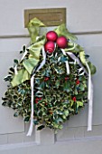 BRUERN COTTAGES  OXFORDSHIRE: CHRISTMAS - DECORATIVE HOLLY WREATH WITH RED BAUBLES AND RIBBON ON FRONT DOOR
