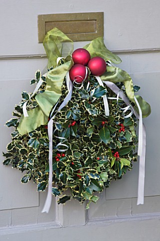 BRUERN_COTTAGES__OXFORDSHIRE_CHRISTMAS__DECORATIVE_HOLLY_WREATH_WITH_RED_BAUBLES_AND_RIBBON_ON_FRONT
