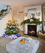 BRUERN COTTAGES  OXFORDSHIRE: CHRISTMAS - THE SITTING ROOM WITH FIREPLACE  CHRISTMAS TREE AND OTTOMAN WITH BOWL OF SATSUMAS