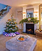BRUERN COTTAGES  OXFORDSHIRE: CHRISTMAS - THE SITTING ROOM WITH FIREPLACE  CHRISTMAS TREE AND OTTOMAN WITH BOWL OF SATSUMAS