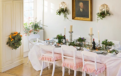 BRUERN_COTTAGES__OXFORDSHIRE_CHRISTMAS__THE_DINING_TABLE_WITH_CANDLES_AND_WREATH_ON_FRONT_DOOR_WITH_