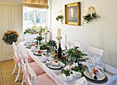BRUERN COTTAGES  OXFORDSHIRE: CHRISTMAS - THE DINING TABLE WITH CANDLES AND WREATH ON FRONT DOOR WITH ORANGE RIBBON