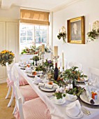 BRUERN COTTAGES  OXFORDSHIRE: CHRISTMAS - THE DINING TABLE WITH CANDLES AND WREATH ON FRONT DOOR WITH ORANGE RIBBON