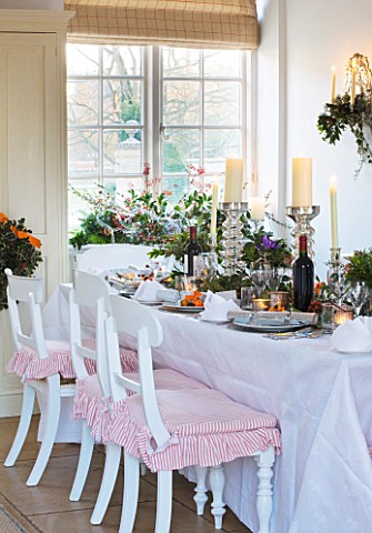 BRUERN_COTTAGES__OXFORDSHIRE_CHRISTMAS__THE_DINING_TABLE_WITH_CANDLES_AND_WREATH_ON_FRONT_DOOR_WITH_