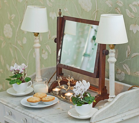 BRUERN_COTTAGES__OXFORDSHIRE_CHRISTMAS__THE_TWIN_BEDROOM__TABLE_WITH_LAMPS__CYCLAMEN_IN_WHITE_TEACUP