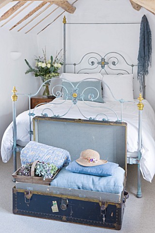 DESIGNER_CAROLYN_MINTY__GLOUCESTERSHIRE__GUEST_BEDROOM_WITH_IRON_BED_AND_VINTAGE_LEATHER_TRUNK