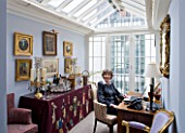 DESIGNER JANE CHURCHILL : JANE CHURCHILL SITS AT HER DESK IN THE CONSERVATORY WITH DRINKS TABLE