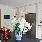 DESIGNER JANE CHURCHILL : THE KITCHEN WITH HAND PAINTED CUPBOARD DOORS BY BIANCA SMITH. GRANITE WORKTOP  LILIES IN VASE