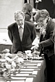 BLACK AND WHITE IMAGE OF JUDGES LOOKING AT CAMELLIAS AT THE RHS CAMELLIA SHOW IN VINCENT SQUARE  LONDON