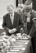 BLACK AND WHITE IMAGE OF JUDGES LOOKING AT CAMELLIAS AT THE RHS CAMELLIA SHOW IN VINCENT SQUARE  LONDON