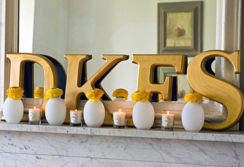 DESIGNER_KALLY_ELLIS__LONDON_FIREPLACE_WITH_FAMILY_INITIALS_AND_EGG_SHAPED_VASES_CONTAINING_RANUNCUL