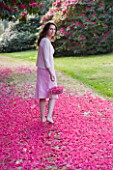 TREGOTHNAN  CORNWALL: GIRL WALKING WITH TRUG FILLED WITH FLOWERS OF RHODODENDRON RUSSELLIANUM