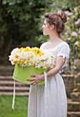 STYLING BY JACKY HOBBS  - GIRL WITH GREEN HAT BOX FILLED WITH NARCISSUS  DAFFODILS  SPRING