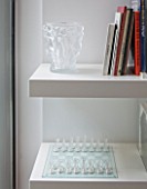CAKE BOY HOUSE  LONDON: LALIQUE VASE AND CHESS SET BENEATH BOOKSHELF IN POOL ROOM IN BASEMENT