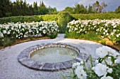 LE JARDIN DALCHIMISTE  PROVENCE  FRANCE; DESIGNERS  ERIC OSSART AND ARNAUD MAURIERES: CIRCULAR POOL SURROUNDED BY WHITE ICEBERG ROSES IN THE WHITE SQUARE