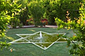 LE JARDIN DALCHIMISTE  PROVENCE  FRANCE: DESIGNERS - ERIC OSSART AND ARNAUD MAURIERES. RED SQUARE WITH 6 POINTED POOL AND FOUNTAIN IN LAWN