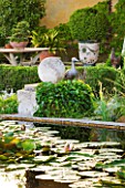 LES CONFINES  PROVENCE  FRANCE - DESIGNER: DOMINIQUE LAFOURCADE - HOUSE SEEN FROM ACROSS THE WATERLILY POND WITH DUCK ORNAMENT AND TABLE