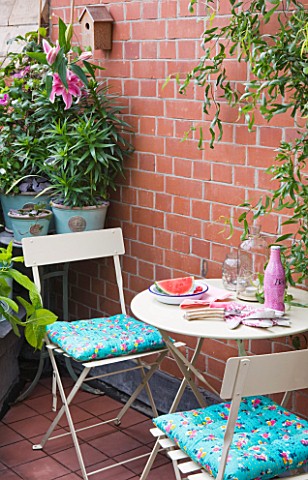 THE_BALCONY_GARDENER__ISABELLE_PALMER__TABLE_AND_CHAIRS_WITH_STRGAZER_LILIES_ON_THE_BALCONY