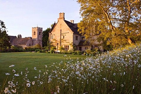 ASTHALL_MANOR__OXFORDSHIRE_THE_HOSUE_SEEN_FROM_OXEEYE_DAISY_MEADOW_BESIDE_THE_LAWN