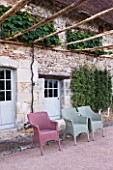 PRIEURE NOTRE-DAME DORSAN  FRANCE: VITIS COIGNETIAE TRAINED AGAINST THE STONE WALLS OF THE PRIORY WITH CHAIRS IN FRONT
