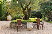 DESIGNER MICHEL SEMINI  PROVENCE  FRANCE: MAS THEO - OLIVE TREE WITH LOW STONE WALL IN GRAVEL COURTYARD - TERRACOTTA CONTAINERS AND METAL SEATS