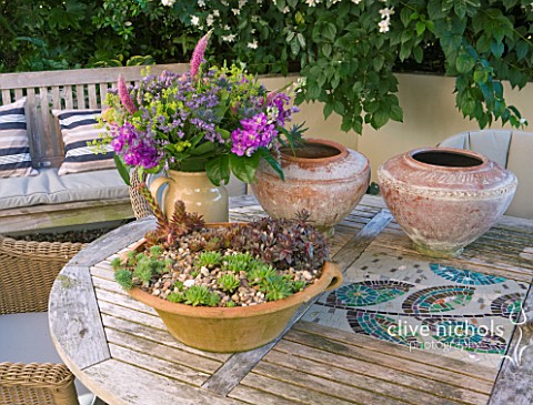 BARBARA_KENNINGTON_GARDEN__BRIGHTON_CONTAINERS_ON_THE_PATIO_TABLE_WITH_MOSAIC_INSETS