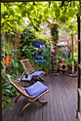 KARLA NEWELL GARDEN  BRIGHTON: WOODEN SEATS ON THE DECKED TERRACE OUTSIDE THE BACK DOOR OF THE HOUSE  WITH TRACHYCARPUS   ORANGE AND BLUE WALLS