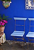KARLA NEWELL GARDEN  BRIGHTON: SMALL TOWN GARDEN - BLUE CAFE CHAIRS BESIDE BLUE PAINTED WALL WITH CERAMIC PICTURE FROM PORTUGAL  CERAMIC CONTAINER AND TERRACOTTA CONTAINER