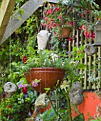 KARLA NEWELL GARDEN  BRIGHTON: SMALL TOWN GARDEN - ORANGE WALL  HANGING BASKETS AND STONES GATHERED FROM THE BEACH