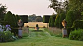 KINGSBRIDGE FARM  BUCKINGHAMSHIRE: FORMAL YEW AVENUE WITH MEADOW GRASS AND CENTRAL FONT AND PLEACHED HORNBEAM  FARMLAND BEYOND