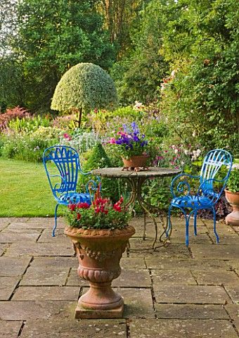 KINGSBRIDGE_FARM__BUCKINGHAMSHIRE_STONE_PATIO__TERRACE_BY_HOUSE_WITH_URN__TABE_AND_BLUE_CHAIRS_AND_P