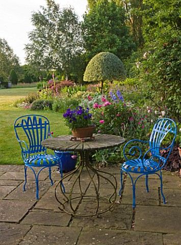 KINGSBRIDGE_FARM__BUCKINGHAMSHIRE_STONE_PATIO__TERRACE_BY_HOUSE_WITH_URN__TABE_AND_BLUE_CHAIRS_AND_P