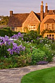 WHATLEY MANOR  WILTSHIRE: VIEW OF THE HOTEL ACROSS THE LAWN AND HERBACEOUS BORDER  AT SUNSET