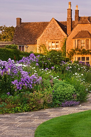 WHATLEY_MANOR__WILTSHIRE_VIEW_OF_THE_HOTEL_ACROSS_THE_LAWN_AND_HERBACEOUS_BORDER__AT_SUNSET