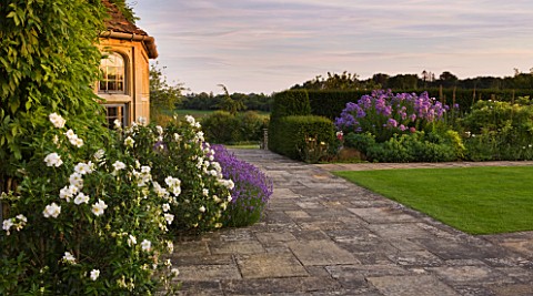 WHATLEY_MANOR__WILTSHIRE_VIEW_OF_THE_HOTEL_WITH_LAWN_AND_HERBACEOUS_BORDER__AT_SUNSET